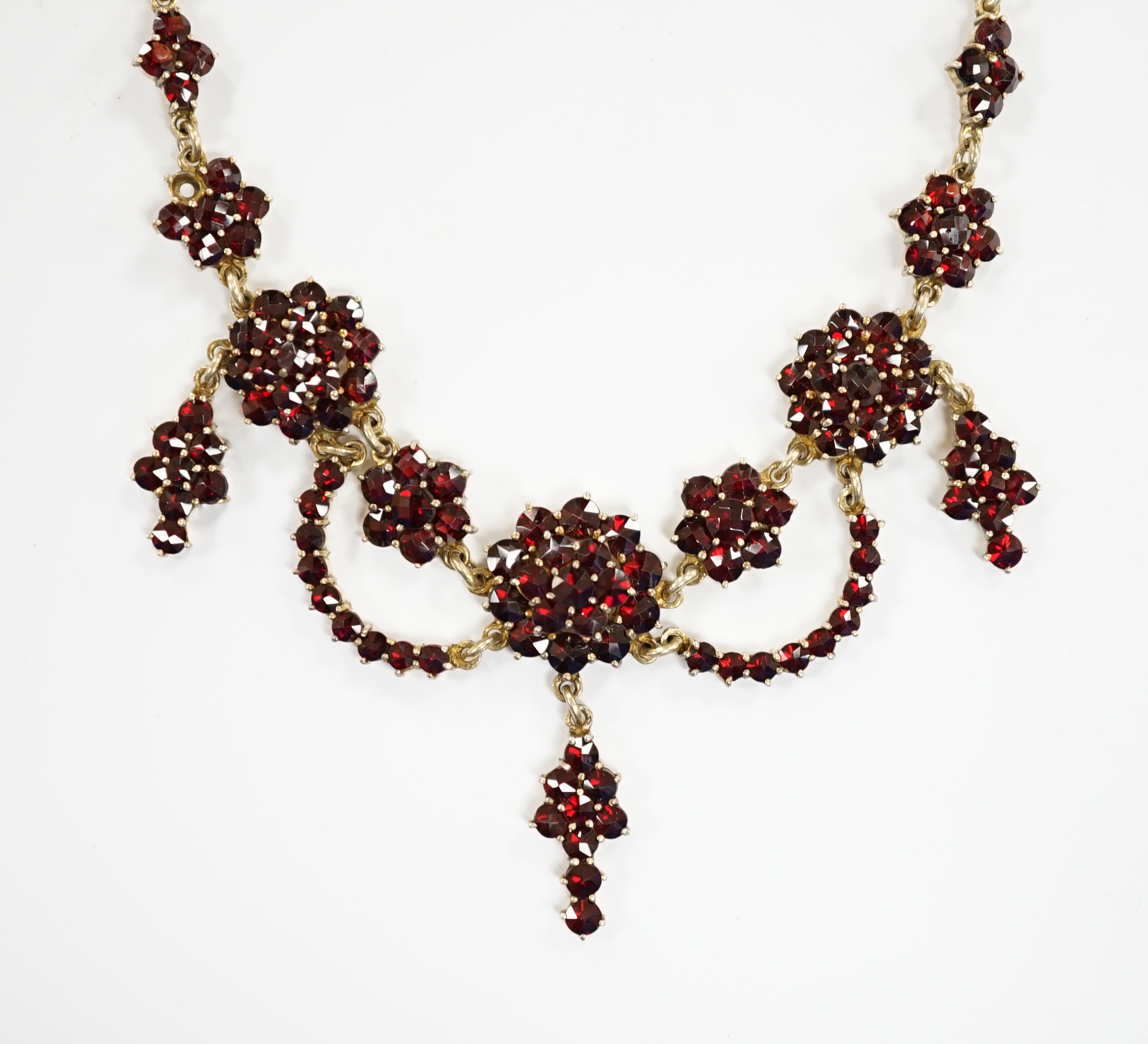 An early 20th century gilt sterling and garnet cluster set drop necklace, 45cm.